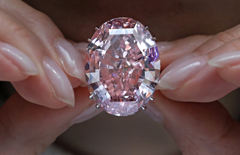 The Pink Star diamond being auctioned, surrounded by eager bidders, emphasizing its status as the most expensive gemstone ever sold.