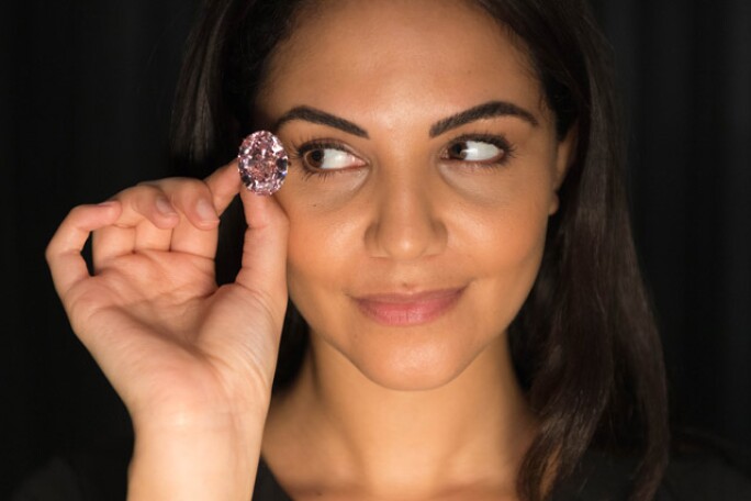 The Pink Star diamond, a flawless 59.60-carat pink gemstone, set against a black background, showcasing its vibrant color and exceptional clarity.