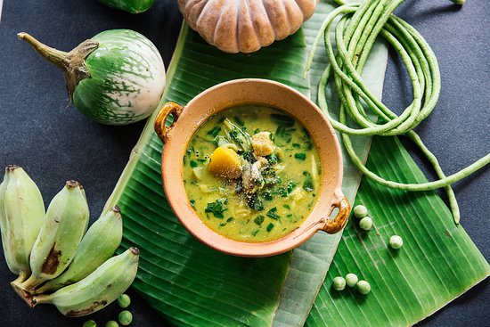 A steaming bowl of Samlor Korkor Soup, filled with fresh vegetables, tender meat, and aromatic herbs, served with jasmine rice