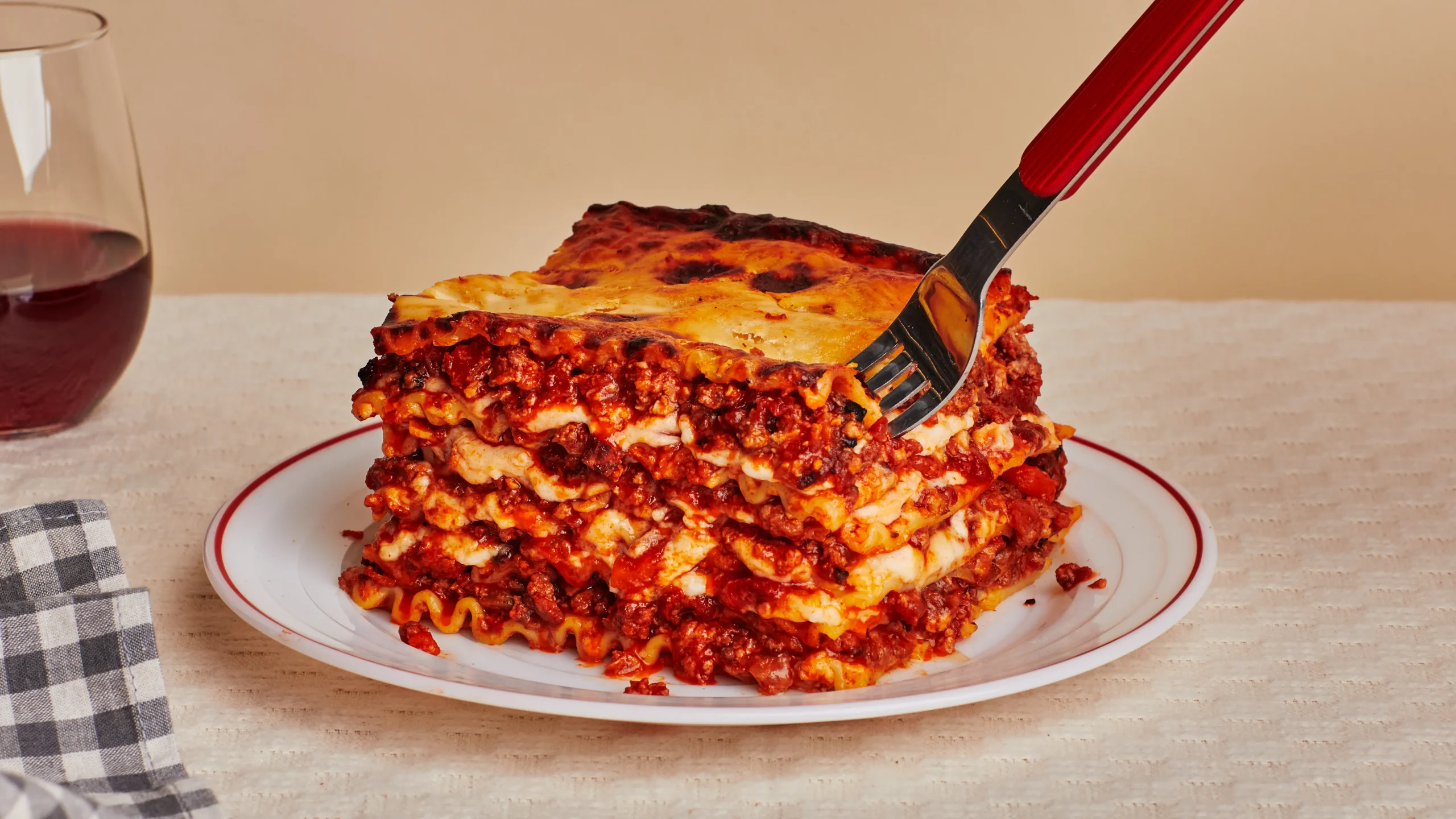 Close-up of a cheesy, meaty lasagna slice on a plate. 