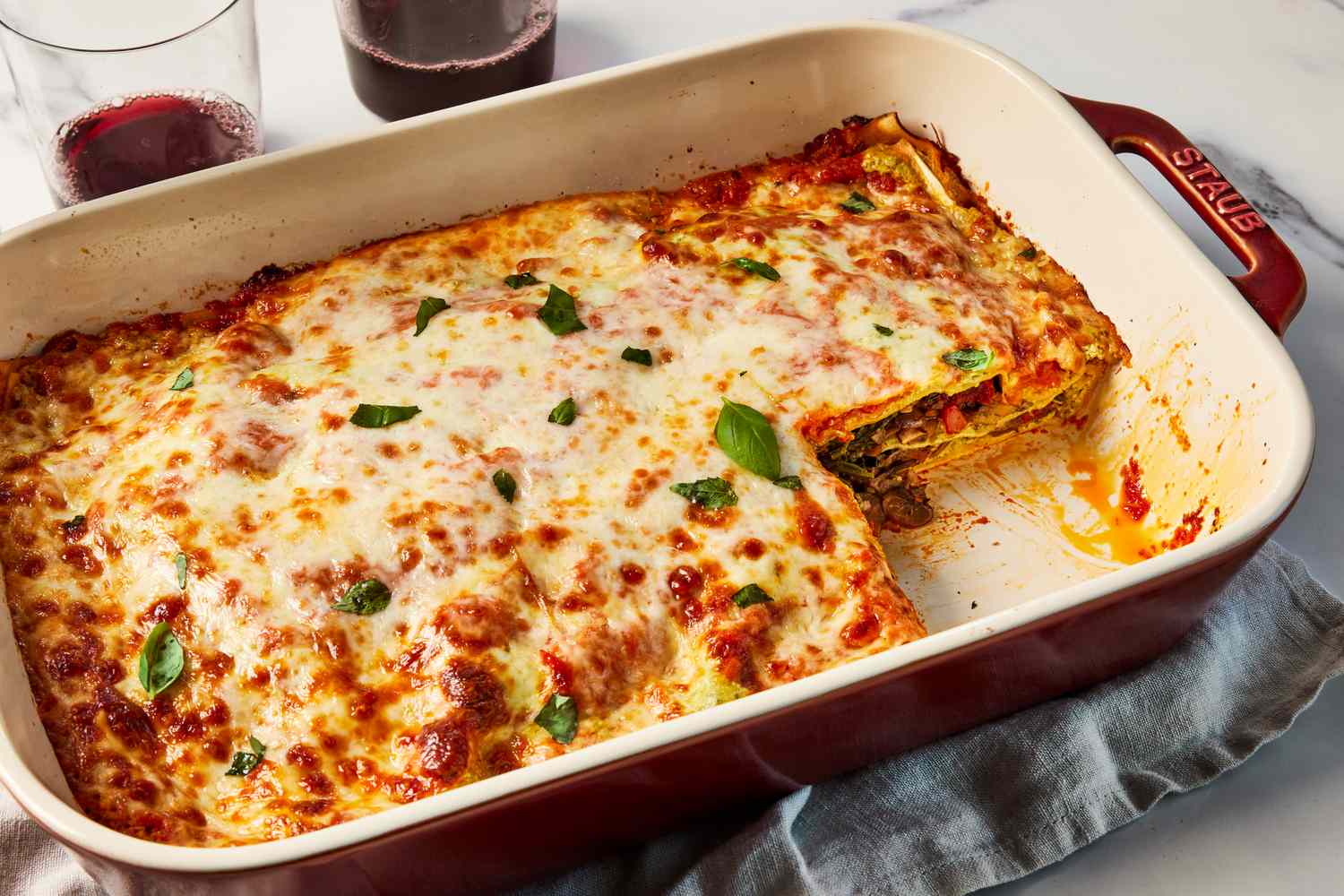 A freshly baked lasagna dish served with basil and garlic bread. 